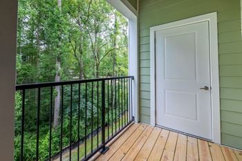 A white door is on the right side of a balcony with a black railing.
